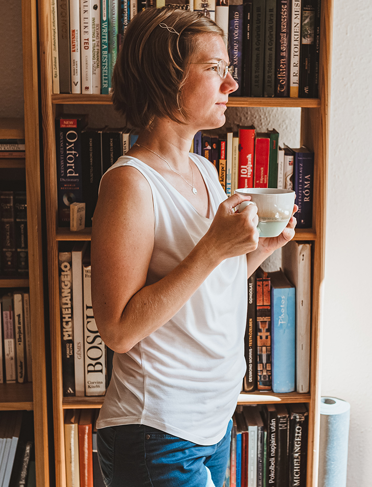 Woman before a bookshelf, thinking about her past.